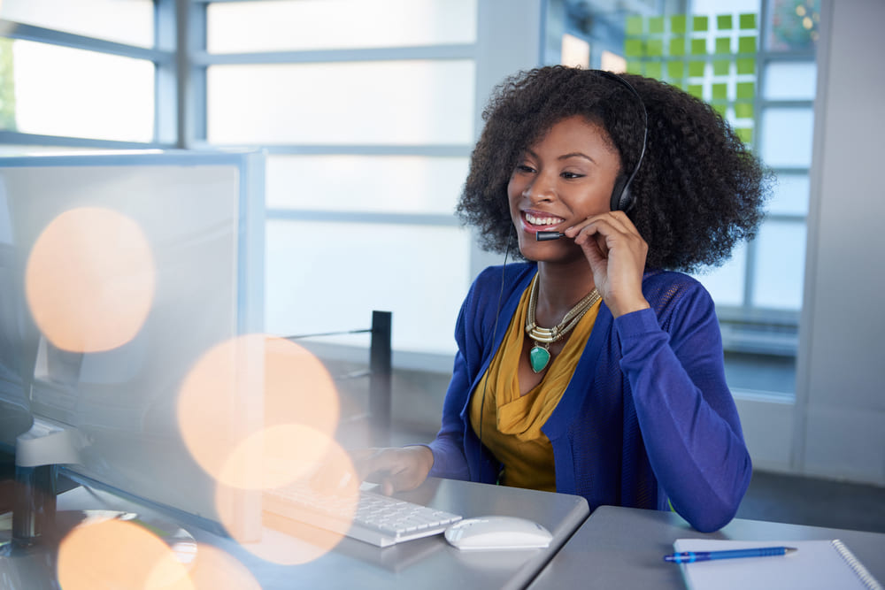 woman smiling on phone while working on laptop