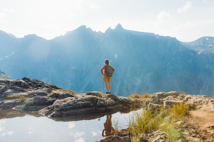 woman stood at the edge of cliff in a mountain range